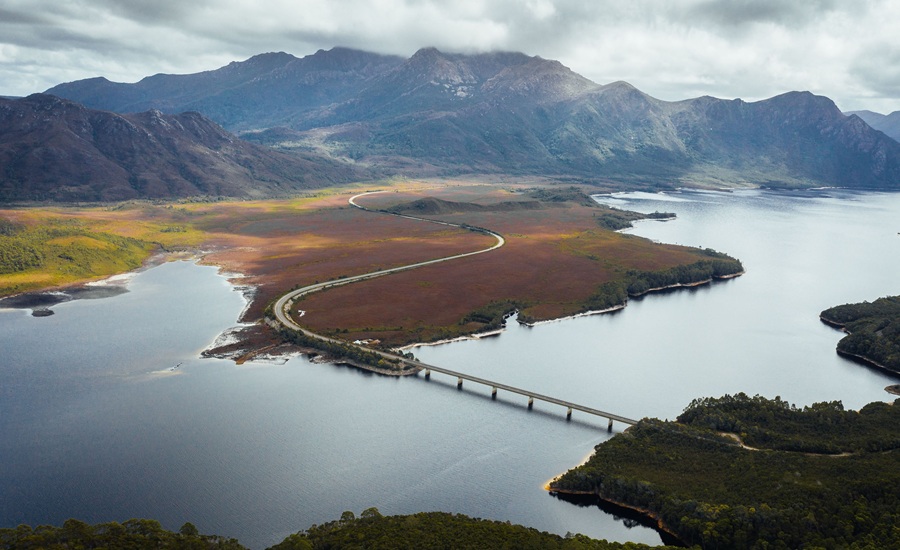 Aerial view of the Lyell Highway crossing the bridge over Lake Burbury with mountain ranges beyond, west coast