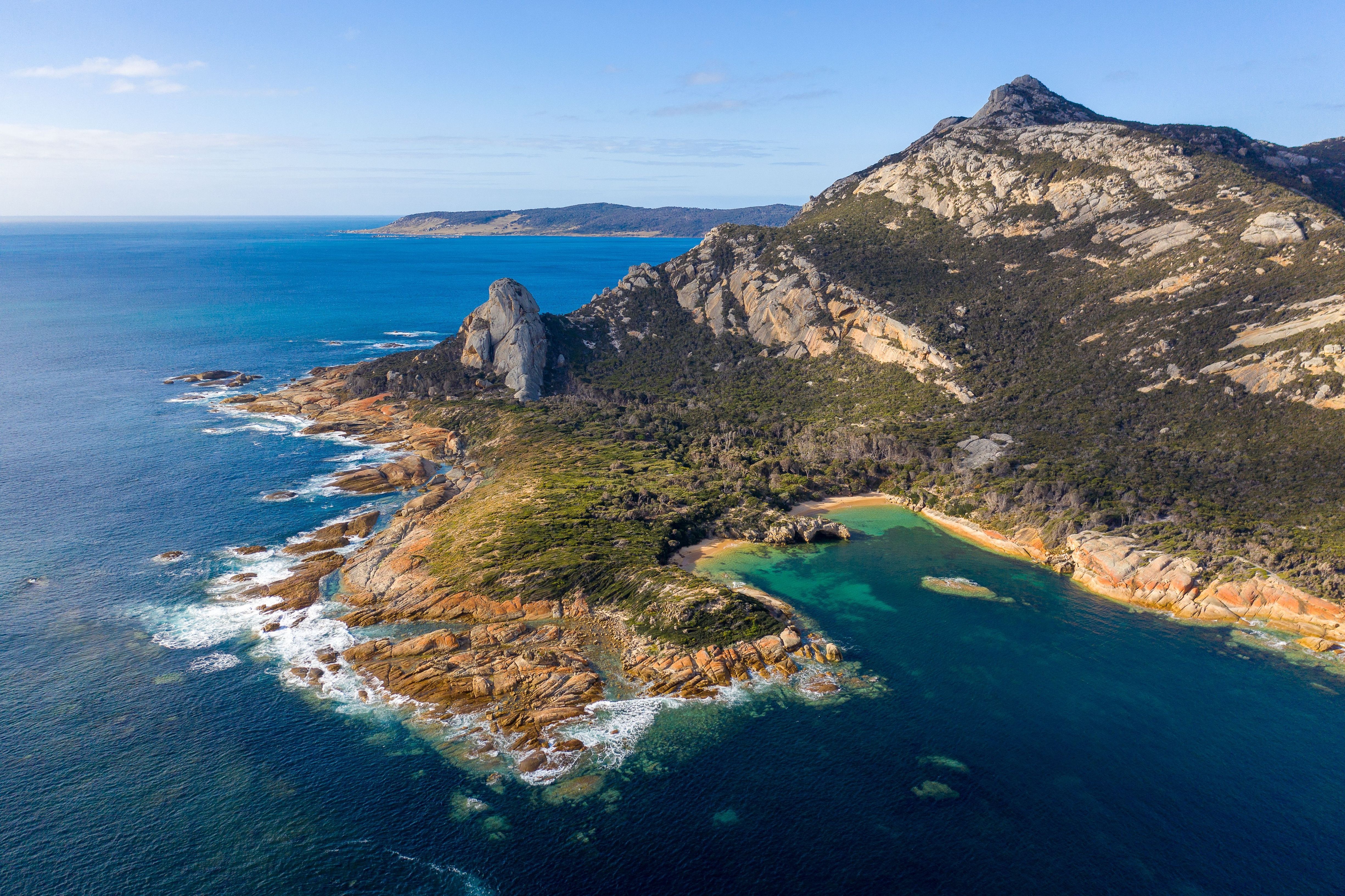 Aerial view of rugged granite coastline and a clear turquoise cove near Killiecrankie, Flinders Island
